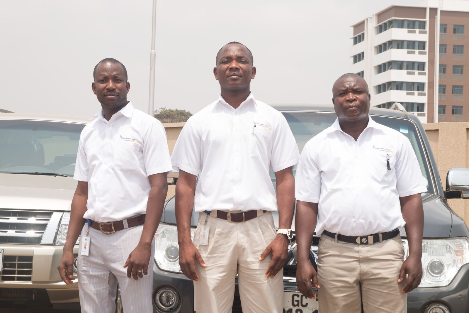 Three uniformed drivers standing in front of company SUVs